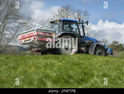 Tracteur avec épandeur, épandage d'engrais granulé sur les prairies, Castle Bolton, Redmire, North Yorkshire, Angleterre, Royaume-Uni Banque D'Images