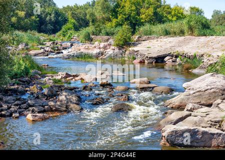 Un ruisseau rapide d'un ruisseau de forêt qui coule à travers des rapides rocheux le long des rives rocheuses. Banque D'Images