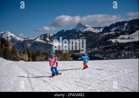 Enfant skier dans la neige. Un garçon et une fille asiatique de snowboard. Sports d'hiver. Les Pléiades, Suisse. Banque D'Images