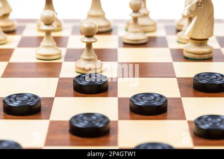 jouer selon différentes règles sur la même carte - les pions noirs et les figures d'échecs blancs sur chessboard en bois, échecs et dames jouant à bord de près Banque D'Images