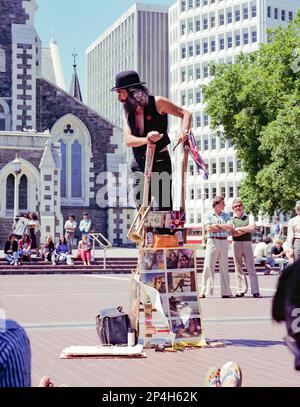 Une image historique de 1981 du magicien de la Nouvelle-Zélande, alias Le magicien se tenant sur une petite échelle en face de la cathédrale de Christchurch. Sur son échelle sont des photos du long métrage de l'époque de la Nouvelle-Zélande, Goodbye Pork Pie. Un an plus tard, en 1982, la New Zealand Art Gallery Directors Association a déclaré qu'à leur avis, le Wizard était une authentique œuvre d'art vivante et que le conseil municipal l'a nommé « Wizard of Christchurch ». Banque D'Images