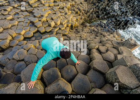 Une femme marche sur une formation rocheuse unique en Irlande Banque D'Images