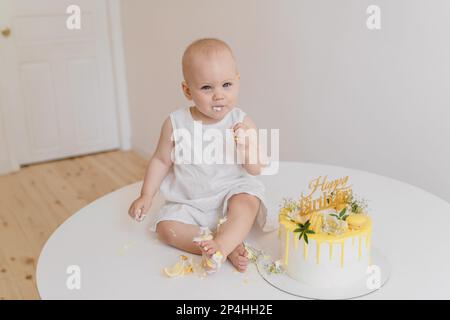 Bébé fille mange un gâteau d'anniversaire avec ses mains et ses jambes Banque D'Images