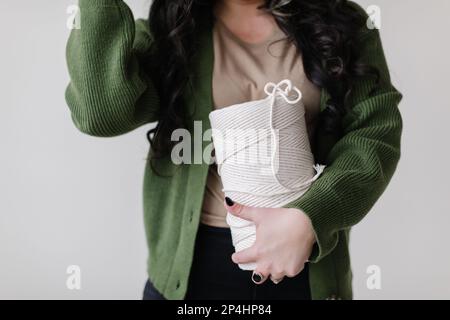 Gros plan d'une femme dans un gilet portant un rouleau de macrame géant Banque D'Images