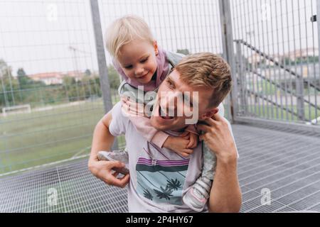 Papa et bébé fille s'amusent près du stade de football Banque D'Images