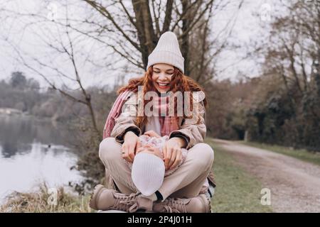 Maman et bébé maussettes s'assoient dans un parc brumeux au bord de la rivière. Banque D'Images