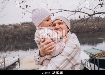 Papa secoue sa fille de deux ans dans les bras et sourit à l'extérieur Banque D'Images