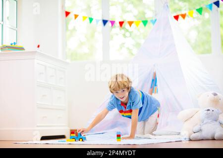 Chambre pour enfants avec tente à tipi. Les enfants jouent dans une chambre blanche ensoleillée. Intérieur lumineux et confortable pour la garderie ou la salle de jeux. Banque D'Images