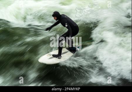 Munich, Allemagne. 06th mars 2023. Un surfeur monte à bord à des températures glaciales sur la vague artificielle de l'Eisbach dans le jardin anglais, situé au coeur de la capitale bavaroise. La vague d'Eisbach est un véritable hotspot à tout moment de l'année. Credit: Peter Kneffel/dpa/Alay Live News Banque D'Images