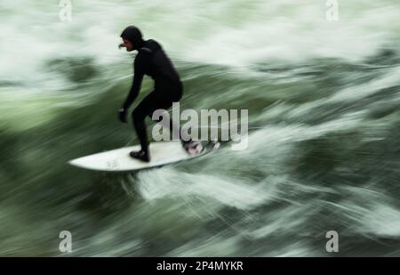 Munich, Allemagne. 06th mars 2023. Un surfeur monte à bord à des températures glaciales sur la vague artificielle de l'Eisbach dans le jardin anglais, situé au coeur de la capitale bavaroise. La vague d'Eisbach est un véritable hotspot à tout moment de l'année. Credit: Peter Kneffel/dpa/Alay Live News Banque D'Images