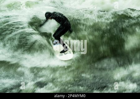 Munich, Allemagne. 06th mars 2023. Un surfeur monte à bord à des températures glaciales sur la vague artificielle de l'Eisbach dans le jardin anglais, situé au coeur de la capitale bavaroise. La vague d'Eisbach est un véritable hotspot à tout moment de l'année. Credit: Peter Kneffel/dpa/Alay Live News Banque D'Images