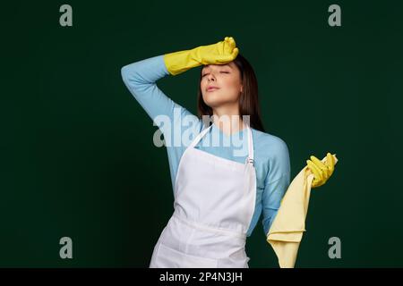 femme fatiguée dans des gants jaunes et un tablier plus propre Banque D'Images