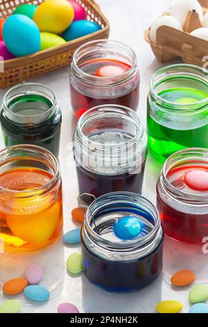 Teindre les œufs de Pâques dans des jarres colorées en verre avec une Candy de Pâques multicolore sur un comptoir en marbre Banque D'Images