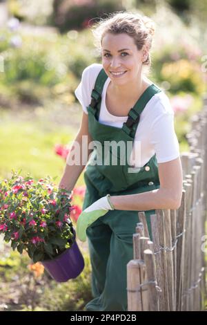 joyeuse femme jardinière tenant un rack de fleurs Banque D'Images