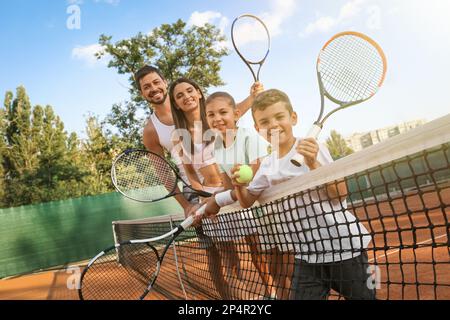 Bonne famille avec des raquettes de tennis sur le court à l'extérieur Banque D'Images