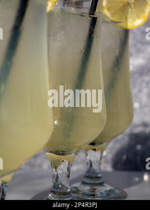 Trois cocktails au citron dans de grands verres sur une table en bois clair Banque D'Images