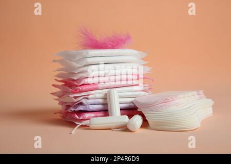 Coussinets menstruels avec plumes roses et autres produits d'époque sur fond orange pâle Banque D'Images