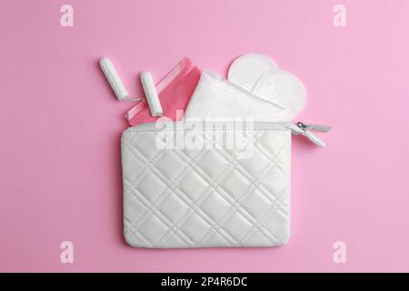 Sac avec tapis menstruels, tampons et pantyliners sur fond rose, couché à plat Banque D'Images