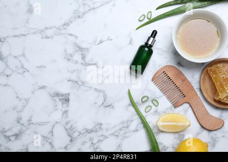 Masque de cheveux fait maison dans un bol, ingrédients et peigne sur une table en marbre blanc, plat. Espace pour le texte Banque D'Images