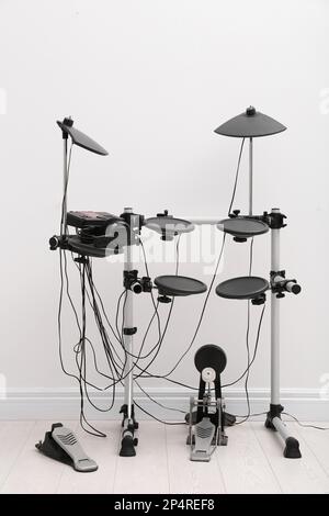 Kit tambour électronique moderne près du mur blanc à l'intérieur. Instrument de musique Banque D'Images