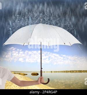 Femme avec parapluie ouvert sous une forte pluie près de la rivière, à proximité Banque D'Images