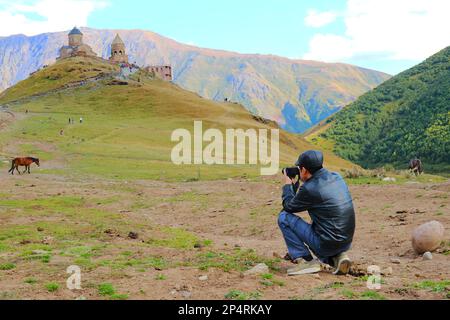 Voyageur photographiant Tsminda Sameba ou l'église de la Trinité de Gergeti, une destination touristique populaire dans la ville de Stepantsminda, Kazbegi, Géorgie Banque D'Images