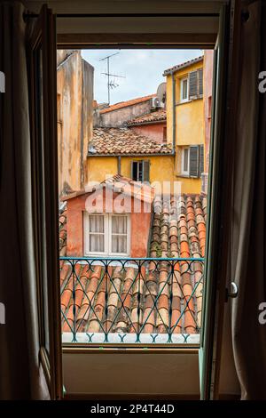 Vue sur le toit d'époque d'Old Nice depuis une fenêtre. Toits en tuiles et murs ocre de style italien traditionnel. Banque D'Images