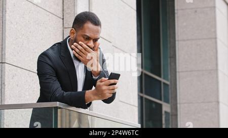 Frustré ethnique afro-américaine barbu triste choqué homme regardant l'écran de smartphone se sentant déçu de reçu mauvais message de stress Banque D'Images
