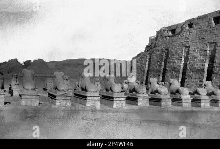 Vers 1940s, historique, une vue de derrière des rangées de statues de sphinx à tête de bélier en pierre sur les plinthes, Temple de Karnak, Louxor Égypte. Un ancien lieu de culte, considéré comme le plus grand site religieux du monde, les ruines égyptiennes de Karnak sont dites comme l'endroit où le dieu Amun a lié avec le peuple de la terre. Banque D'Images