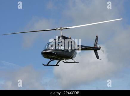 Un hélicoptère Agusta-Bell AB-206A JetRanger vole le long de la piste d'un aérodrome de East Sussex Banque D'Images