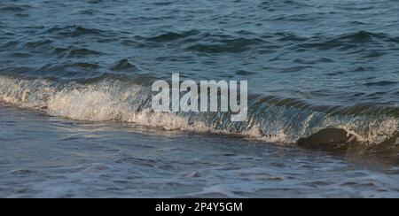 Une grande et forte onde de tempête de couleur turquoise avec des éclaboussures de mousse blanche coule et se brise sur le rivage. Banque D'Images