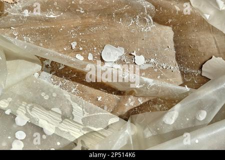 Revêtement de parquet avec feuille transparente pour la peinture des murs. Taches de peinture blanche, taches et poussières sur le film plastique transparent. Banque D'Images