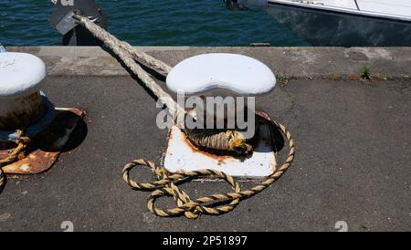 Un bollard rouillé avec des cordes marines usées attaché à côté de l'eau Banque D'Images