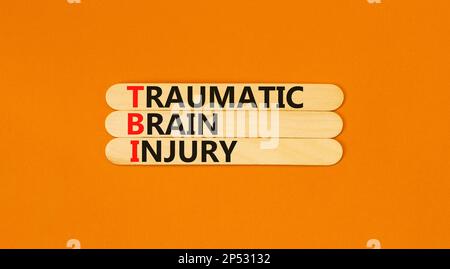 Symbole de lésion cérébrale traumatique TBI. Mots-clés TBI traumatisme crânien sur bâton de bois sur une belle table orange fond orange. Médical et Banque D'Images