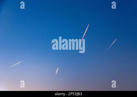 de nombreux contrails d'avion en début de matinée soleil au ciel Banque D'Images