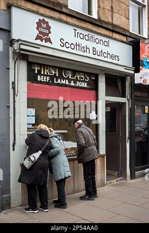 Les clients qui regardent la fenêtre de la boutique traditionnelle Scottish Butchers à Newington, Édimbourg, Écosse, Royaume-Uni. Banque D'Images