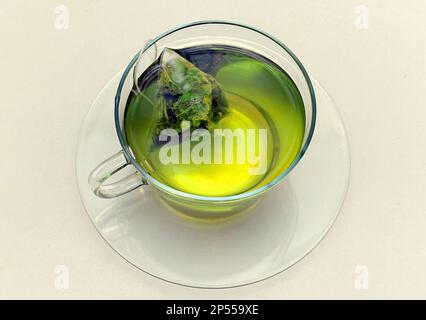 Sachet de thé vert en perles de jasmin dans une tasse de verre isolée sur fond blanc Banque D'Images