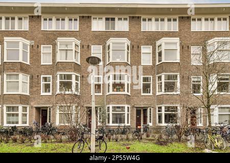 un immeuble d'appartements avec des vélos garés à l'avant et de l'autre côté, il y a un vélo incliné contre le mur Banque D'Images