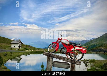 Vieille moto sur un podium en bois, le fond est le ciel bleu avec des nuages. Livigno, Alpes, Italie Banque D'Images