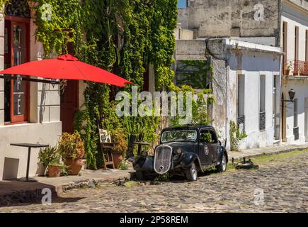 Colonia del Sacramento, Uruguay - 5 février 2023 : ancienne voiture ancienne près d'un bar ou d'un café local dans une rue pavée Banque D'Images