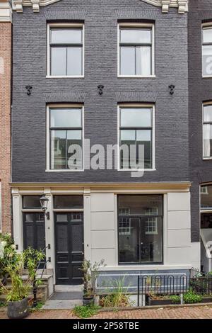 Amsterdam, pays-Bas - 10 avril 2021 : un immeuble d'appartements au centre d'amsterdam, où il y a des plantes et des pots de chaque côté de la maison Banque D'Images
