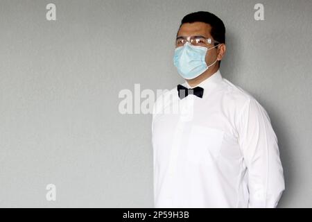 Latino serveur homme avec masque de protection, travaille avec des gants en latex, nouveau normal dans les restaurants, Covid-19 Banque D'Images