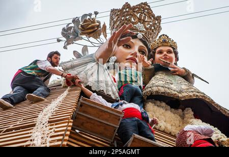 Les hommes plaçant des offrandes de fleurs sur une grande réplique en bois statue de Virgen de los Desamparados, festival Fallas, Plaza de la Virgen Square, Valence Banque D'Images