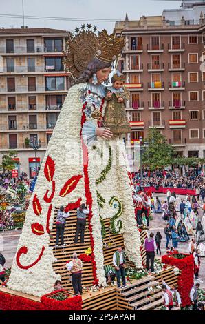 Les hommes plaçant des offrandes de fleurs sur une grande réplique en bois statue de Virgen de los Desamparados, festival Fallas, Plaza de la Virgen Square, Valence Banque D'Images