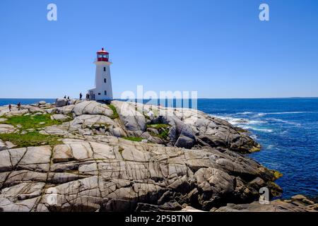 Touristes marchant sur des formations rocheuses au phare de Peggy's Cove, Nouvelle-Écosse, Canada Banque D'Images