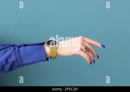 Woman with golden wristwatch on blue background Stock Photo