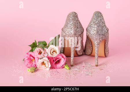 Chaussures élégantes à talons hauts pour femmes et magnifiques fleurs sur fond rose Banque D'Images
