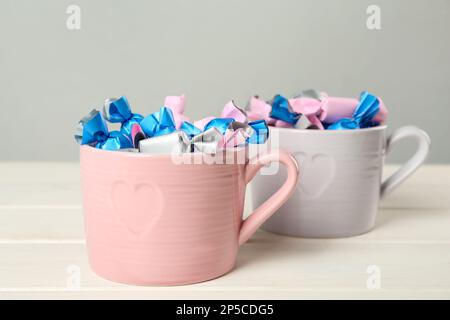 Bonbons dans des emballages colorés sur une table en bois blanc Banque D'Images