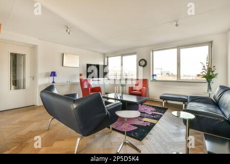 un salon avec des chaises en cuir noir et une table basse devant le canapé se trouve sur le parquet Banque D'Images