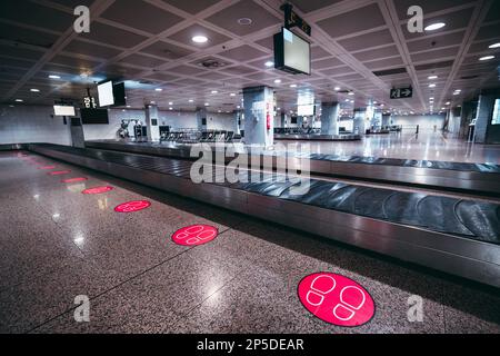 Une zone de retrait des bagages à l'aéroport de Lisbonne, à clé basse. Sur le sol, cercles avec dessins de deux pieds, pour que les gens maintiennent une distance de sécurité comme Banque D'Images